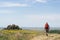 Hiker with a red backpack on a trail with yellow flowers, in Macin Mountains, oldest mountains in Romania