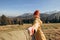 Hiker with red hat stands on edge of cliff against background and extends a hand. Happy woman gives a hand to someone