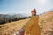 Hiker with red hat stands on edge of cliff against background and extends a hand. Happy woman gives a hand to someone