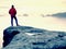 Hiker in red jacket enjoy view over clouds. Mountain rocky peak