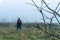 A hiker with red ruck sack standing in the distance in a out of focus. On a foggy, winters day in the countryside