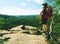 Hiker in shorts wear cowboy hat and red back pack, stay on rock