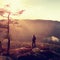 Hiker stand at heather bush on the corner of empire bellow pine tree and watch over misty and foggy morning valley