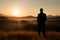 Hiker stand on meadow with golden stalks of grass and watch over the misty and foggy morning valley to sunrise