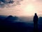 Hiker stand on the sharp corner of sandstone rock in rock empires park and watching over the misty and foggy morning valley to Sun