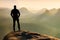 Hiker is standing on the peak of sandstone rock in rock empires park and watching over the misty and foggy morning valley to Sun.