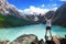 Hiker standing with raised hands near the beautiful mountain lake and enjoying valley view