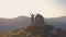 Hiker standing on top of rocky mountain enjoying magnificent view. Mountaineer looking at sunrise in mountains.