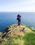 A hiker stands at a coastal cliff in Scotland