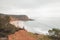 Hiker stands on the edge of a cliff and watches the beach below called Praia do Burgau on the southwest coast of Portugal in the