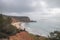 Hiker stands on the edge of a cliff and watches the beach below called Praia do Burgau on the southwest coast of Portugal in the