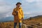 Hiker in stylish coat and hat looking at the landscape