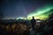 hiker, surrounded by aurora borealis and australis, on night hike through the mountains