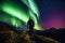 hiker, surrounded by aurora borealis and australis, on night hike through the mountains