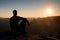 Hiker take relaxing on a rock and enjoying sunset at horizon. Vivid effect.