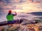 Hiker takes selfie photo, fall nature adventure. Man sit on stone