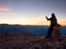 Hiker takes selfie photo. Man sit on Austria Germany border stone on Alpine mountain.