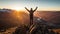 Hiker on top of a mountain with arms raised enjoying the sunrise