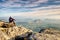 Hiker in trekking clothes sit alone on rock summit. Wonderful daybreak in mountains