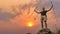 Hiker with trekking stick hiking success on rocky hill top at sunset sky