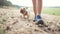 hiker trip. a tourist girl walks on the sand in a forest park with a backpack on her legs close-up next to a faithful