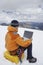 Hiker Using Laptop On Snowy Mountain Landscape