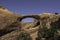 A hiker is visible through a large sandstone arch formation