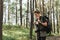 Hiker walking with a backpack and modern mirrorless camera in green forest