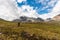 Hiker is walking in the mountains with a backpack and a stick.