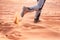 Hiker walking throught sandy desert. Traces in sand. Focus on a man legs. Tourist in a desert. Sandy background.