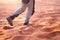 Hiker walking throught sandy desert. Traces in sand. Focus on a man legs. Tourist in a desert. Sandy background.