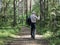 Hiker walks along a forest path and does not stop, gives a sign with his hand