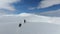 A hiker walks on snow in the mountain with dogs