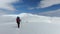 A hiker walks on snow in the mountain with dogs