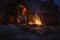 Hiker warms their feet next to a campfire at dusk camping in the woods