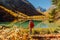 Hiker woman enjoying at lake in autumnal mountains. Mountain lake and tourist