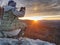 Hiker woman photographer takes photos from sharp cliff edge