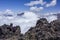 A hiker woman taking a rest and staring at a beautiful view of clouds over the mountains in the High Altlas, Morocco