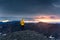 Hiker woman in yellow jacket standing on volcanic mountain and midnight sun from Blahnjukur trail in Icelandic highlands