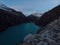 Hiker in yellow jacket at blue turquoise alpine mountain lake Laguna Paron in Caraz Huaraz Ancash Cordillera Blanca Peru