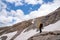 Hiker with yellow raincoat standing on rock against snowy mountain