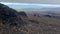 Hikers with backpacks and trekking poles walk the autumn tundra.