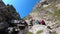 Hikers climb a steep and difficult rocky path in the Italian Alps. Trail for experienced hikers. Path to the Benigni retreat