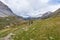 Hikers climbing uphill on steep rocky mountain trail. Summer adventures and exploration on the Alps. Dramatic sky with storm cloud