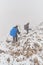 Hikers descending between snow and rocks into a foggy trail in Piatra Craiului mountains part of Carpathians, Romania