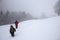 Hikers go up on snow slope in winter. Tourists trekking in winter mountains in fog