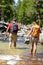 Hikers group walking barefoot crossing river