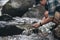 Hikers hand holding transparent clear water from waterfall with backpacks on the rock and water on stream in the forest. hiking