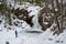 Hikers near frozen Kinsman Falls in Franconia Notch State Park during winter . New Hampshire mountains. USA