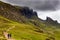 Hikers on a spectacular remote, rocky landscape with a low, moody sky Quiraing, Isle of Skye